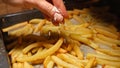 Closeup of female hand pouring salt on frying french fries potatoes on baking pan. Fast food, healthy nutrition, cooking in oven Royalty Free Stock Photo