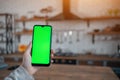 closeup of female hand using smartphone with green screen mockup at home kitchen Royalty Free Stock Photo