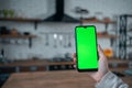 closeup of female hand using smartphone with green screen mockup at home kitchen Royalty Free Stock Photo