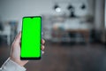 closeup of female hand using smartphone with green screen mockup at home kitchen Royalty Free Stock Photo