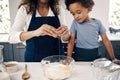 Closeup of female hands cracking a egg into a bowl while baking at home with her son. Woman adding ingredients to a