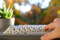 Closeup female hands of elderly woman typing text on computer keyboard in garden, concept of learning to use computer at any age, Royalty Free Stock Photo