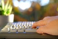 Closeup female hands of elderly woman typing text on computer keyboard in garden, concept of learning to use computer at any age, Royalty Free Stock Photo