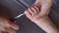 Closeup of female hands holding scissors to cut toe nails on tiny baby foot. Mom taking care of her child s hygiene Royalty Free Stock Photo