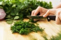 Female hands with knife chopping dill on wooden cutting board Royalty Free Stock Photo