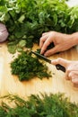 Female hands with knife chopping dill on wooden cutting board Royalty Free Stock Photo