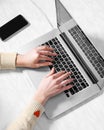 Closeup female hands on laptop keyboard. View from above. Young woman using computer and smartphone sitting at office Royalty Free Stock Photo