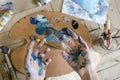 Closeup of female hands mixing paint on a palette at workshop. Artist Royalty Free Stock Photo