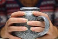 Closeup of female hands with a mug of beverage. Young hipster woman in Christmas sweater holding cup of tea or coffee Royalty Free Stock Photo