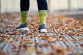 Close-up of a female legs on wooden walking trails covered with autumn leaves