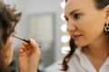 Closeup of female makeup artist applying cosmetic tonal foundation for face sculpting of pretty young woman in beauty Royalty Free Stock Photo