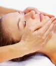 Closeup of a female receiving a facial massage. Closeup of a young woman relaxing at a dayspa , masseuses hand on her Royalty Free Stock Photo