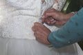 Closeup of a female's hands zipping up the bride's dress