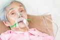 Closeup of female senior patient putting inhalation or oxygen mask in hospital bed or home,sick elderly asian woman undergoing Royalty Free Stock Photo