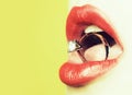 Closeup of female sexy lips with red lipgloss holding round gold ring as present with gem in open mouth with tongue. Royalty Free Stock Photo