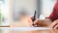 Closeup female signing document focus on her hand holding pen putting signature. Royalty Free Stock Photo