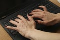 Closeup of a female typing on a black laptop on the table under the lights Royalty Free Stock Photo