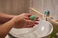 Closeup of a female washing her hands with a bar of soap under the lights in a bathroom Royalty Free Stock Photo