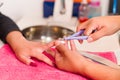 Closeup females hands getting manicure treatment from woman using nail scissors in salon environment, pink towel surface Royalty Free Stock Photo