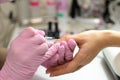 Closeup females hands getting manicure treatment from woman using small brush in salon environment, pink towel surface, blurry Royalty Free Stock Photo