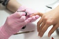 Closeup females hands getting manicure treatment from woman using small brush in salon environment, pink towel surface, blurry Royalty Free Stock Photo