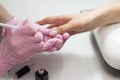 Closeup females hands getting manicure treatment from woman using small brush in salon environment, pink towel surface, blurry Royalty Free Stock Photo