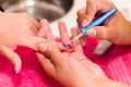Closeup females hands getting manicure treatment from woman using small brush in salon environment, pink towel surface Royalty Free Stock Photo