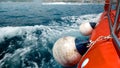 Closeup of fenders, ropes and buoys hanging on the side of red boat sailing in sea bay Royalty Free Stock Photo