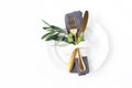 Closeup of festive table summer setting with golden cutlery, olive branch, grey linen napkin, porcelain dinner plate and
