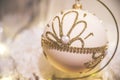 Closeup of festive white christmas bulb with gold glitter patterns among christmas decorations. Beautiful bokeh, electric warm Royalty Free Stock Photo