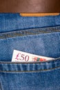 Closeup of fifty pounds sterling banknotes peeking out of blue jeans back pocket