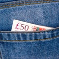 Closeup of fifty pounds sterling banknotes peeking out of blue jeans back pocket