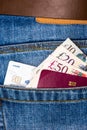 Closeup of fifty, twenty, ten pounds sterling banknotes, contactless credit card and EU passport peeking out of blue jeans back Royalty Free Stock Photo