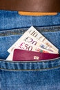 Closeup of fifty, twenty, ten pounds sterling banknotes and EU passport peeking out of blue jeans back pocket Royalty Free Stock Photo