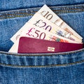 Closeup of fifty, twenty, ten pounds sterling banknotes and EU passport peeking out of blue jeans back pocket Royalty Free Stock Photo