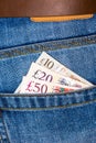 Closeup of fifty, twenty and ten pounds sterling banknotes peeking out of blue jeans back pocket Royalty Free Stock Photo