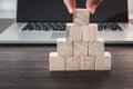 Closeup finger man is pick up wooden cube from stack in front of computer laptop., Business and technology concept Royalty Free Stock Photo