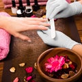 Closeup finger nail care by manicure specialist in beauty salon.