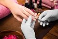 Closeup finger nail care by manicure specialist in beauty salon.