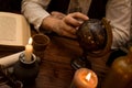 Closeup finger pointing to a globe, medieval table with candles and a old book