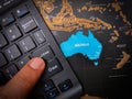 Closeup of a finger pressing "enter" on a black keyboard on top of the Australia map Royalty Free Stock Photo