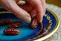closeup of fingers picking a date from a blueandgold plate Royalty Free Stock Photo