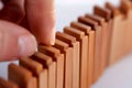 closeup of fingers steadying a domino piece in a row Royalty Free Stock Photo