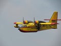 Closeup of a firefighting aircraft in yellow and red flying in the blue sky