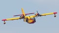 Closeup of a firefighting aircraft in yellow and red flying in the blue sky