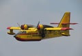 Closeup of a firefighting aircraft in yellow and red flying in the blue sky