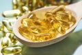 Closeup fish oil dietary supplement. Wooden spoon of oil fish capsules. Omega 3 pills fish oil capsules Royalty Free Stock Photo