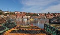 Closeup of fishing net and lobster cages at Whitby harbor and the coastline with moored boats Royalty Free Stock Photo