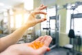 Closeup of fitness woman hands showing vitamin e capsule omega-3, gym background. Healthy lifestyle, medicine, nutritional Royalty Free Stock Photo