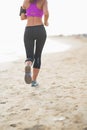 Closeup on fitness woman running on the beach . rear view